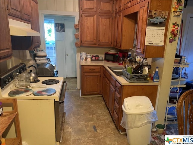 912 S 1st St, Temple, TX 76504 - kitchen with white electric stove, under cabinet range hood, light countertops, and brown cabinetry