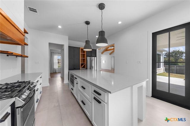 kitchen featuring pendant lighting, a center island, white cabinets, light tile patterned floors, and appliances with stainless steel finishes