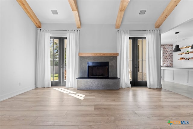 unfurnished living room featuring french doors, beamed ceiling, and light wood-type flooring