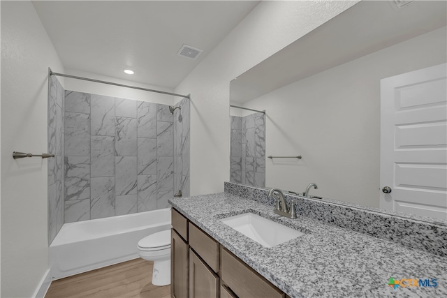 full bathroom featuring hardwood / wood-style flooring, vanity, toilet, and tiled shower / bath