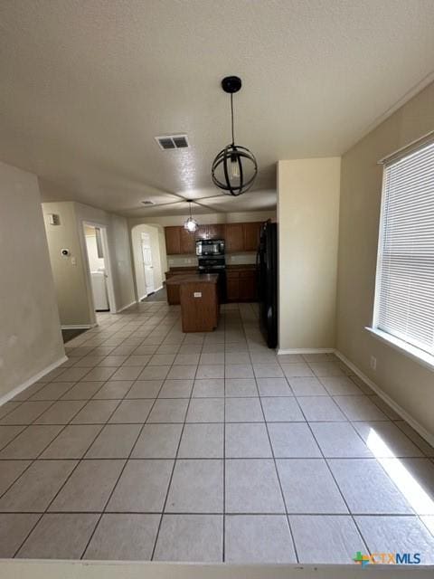 221 Roadrunner Ave, New Braunfels, TX 78130 - kitchen featuring black appliances, light tile patterned floors, a center island, dark countertops, and hanging light fixtures