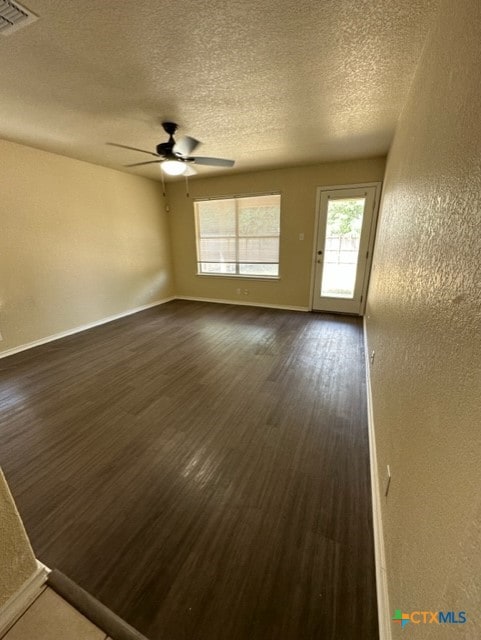 221 Roadrunner Ave, New Braunfels, TX 78130 - empty room with a textured ceiling, dark wood-style flooring, a ceiling fan, and a textured wall