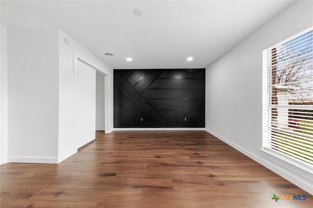 unfurnished room with wooden walls and dark hardwood / wood-style flooring