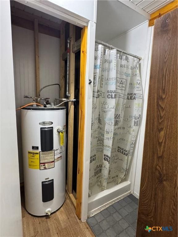 full bath featuring electric water heater, wood finished floors, and a shower stall