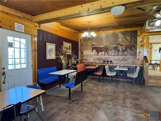 dining space featuring visible vents, beamed ceiling, concrete floors, and a chandelier
