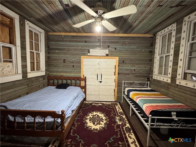 bedroom with wooden walls, wooden ceiling, and a ceiling fan