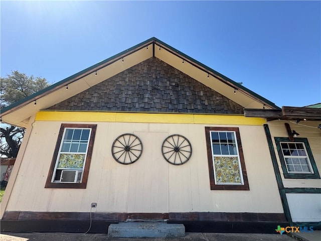 view of side of home with roof with shingles