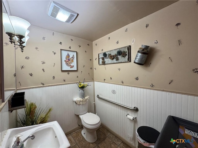 bathroom with tile patterned floors, a wainscoted wall, and toilet