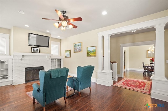 living room with ceiling fan, a fireplace, and dark wood-type flooring