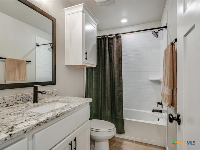 full bathroom featuring hardwood / wood-style floors, vanity, toilet, and shower / tub combo with curtain