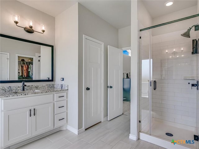 1701 Meadow Crest Dr, Salado, TX 76571 - bathroom featuring a stall shower, vanity, baseboards, a walk in closet, and tile patterned floors