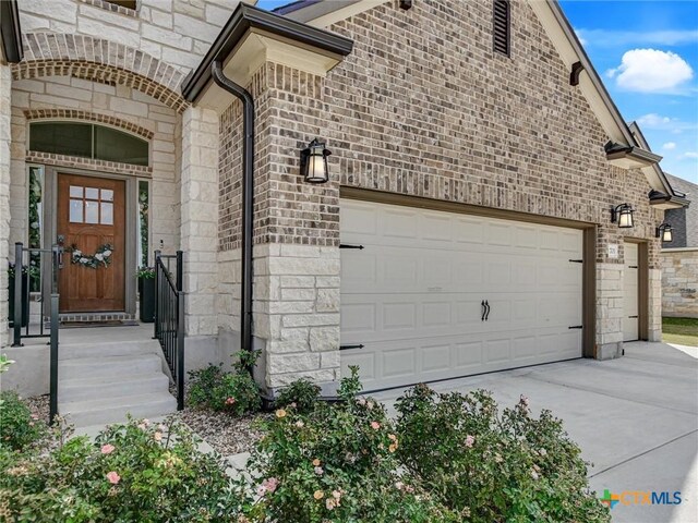 1701 Meadow Crest Dr, Salado, TX 76571 - property entrance featuring an attached garage, concrete driveway, stone siding, and brick siding