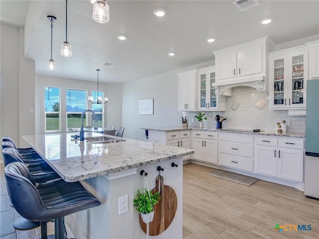 1701 Meadow Crest Dr, Salado, TX 76571 - kitchen featuring a sink, backsplash, black electric cooktop, light stone countertops, and white cabinets