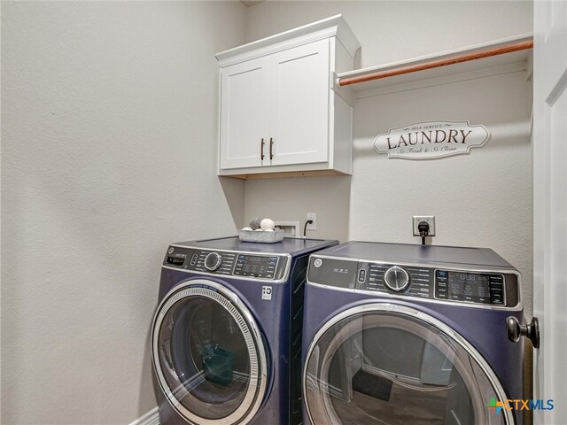 clothes washing area featuring washing machine and dryer and cabinets