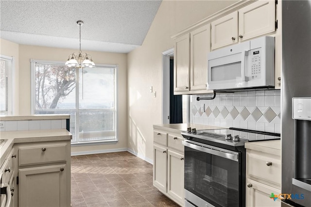 kitchen with a notable chandelier, a healthy amount of sunlight, decorative backsplash, and stainless steel appliances