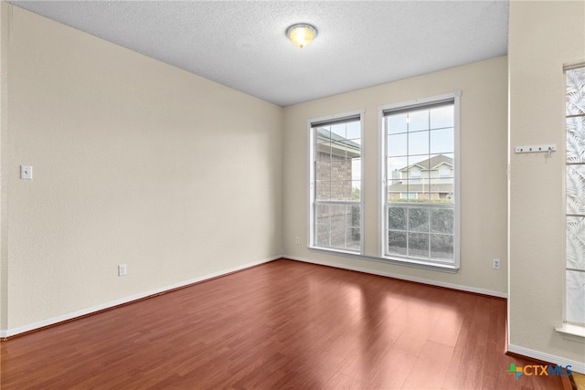 empty room featuring a textured ceiling and dark wood-type flooring