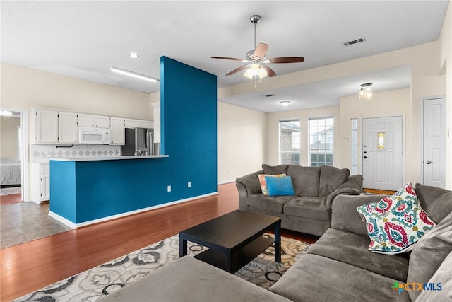 living room with light hardwood / wood-style flooring and ceiling fan