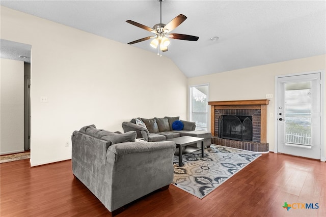 living room with a fireplace, ceiling fan, dark hardwood / wood-style flooring, and vaulted ceiling