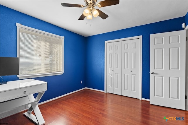 unfurnished office with ceiling fan and dark hardwood / wood-style floors