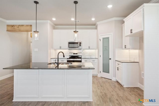 kitchen with pendant lighting, white cabinets, sink, an island with sink, and appliances with stainless steel finishes