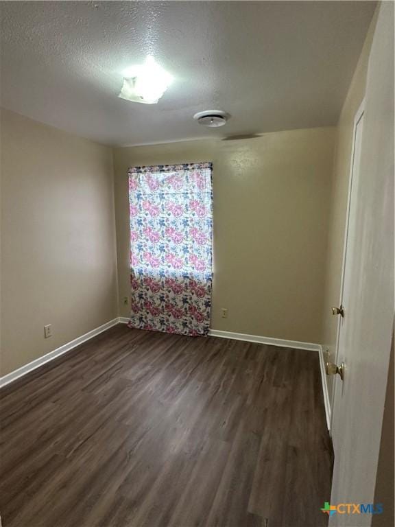 unfurnished room featuring a textured ceiling, baseboards, and dark wood-style flooring