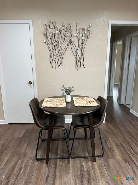 dining area featuring baseboards, wood finished floors, and a textured wall