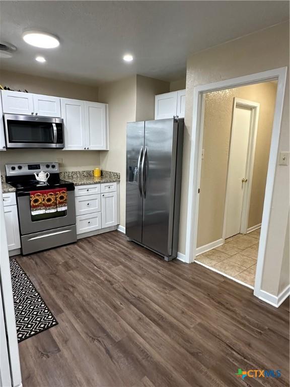 kitchen featuring baseboards, white cabinets, dark wood-style floors, appliances with stainless steel finishes, and stone counters