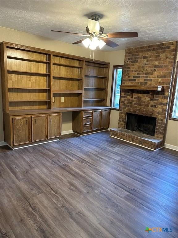 unfurnished living room with a textured ceiling, ceiling fan, a fireplace, and dark hardwood / wood-style floors