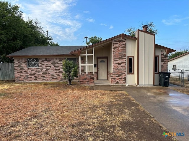 mid-century inspired home with brick siding, a chimney, and fence