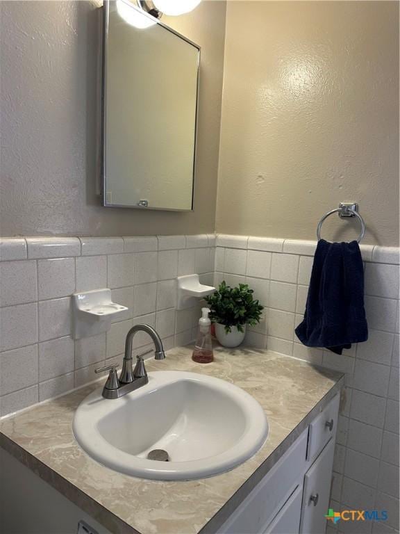 bathroom featuring tile walls, wainscoting, and vanity