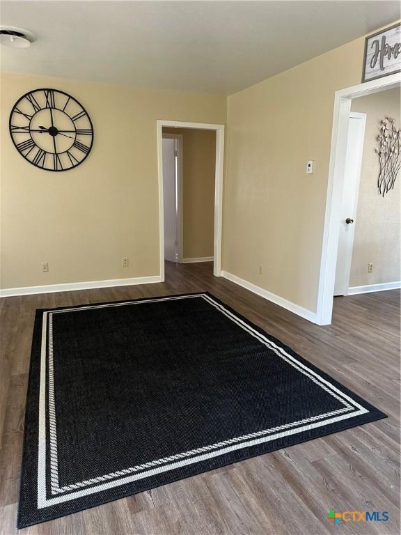 empty room featuring wood finished floors and baseboards