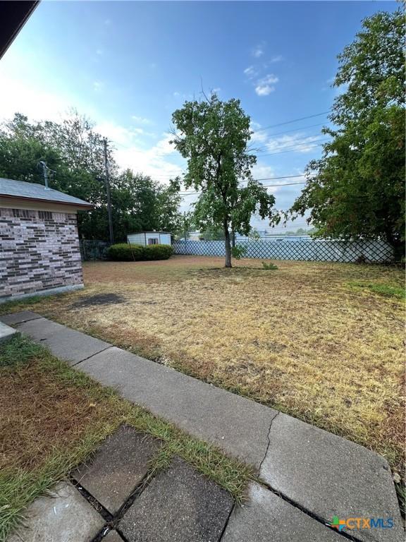 view of yard featuring an outdoor structure and fence