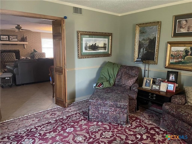 living area featuring light tile patterned floors, ceiling fan, a fireplace, ornamental molding, and a textured ceiling