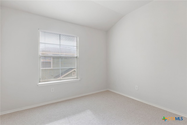 carpeted spare room featuring plenty of natural light and vaulted ceiling