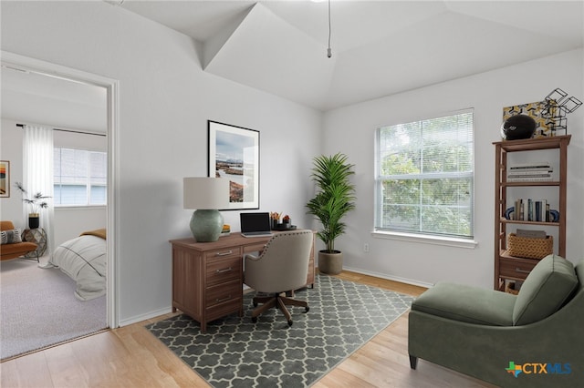 home office featuring a wealth of natural light, lofted ceiling, and hardwood / wood-style flooring