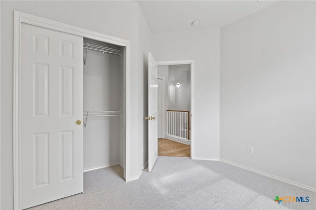 unfurnished bedroom with light colored carpet and a closet