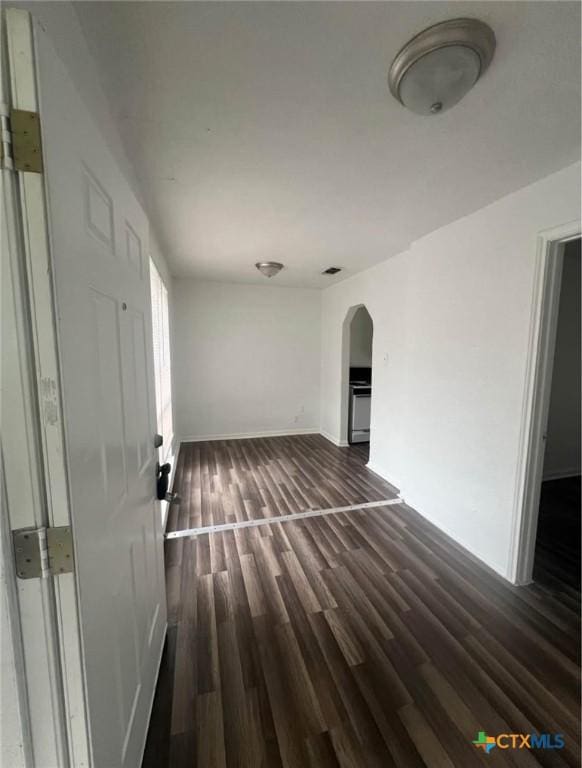 interior space with arched walkways, baseboards, visible vents, and dark wood-style floors