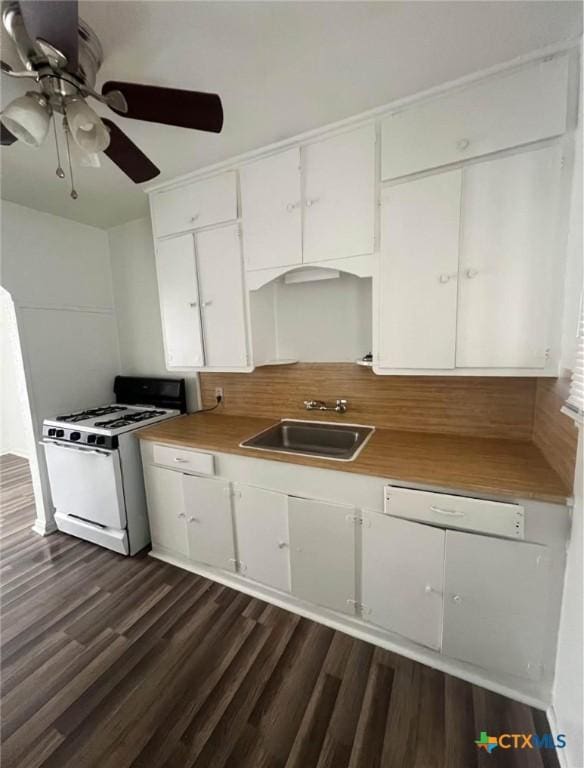 kitchen featuring white cabinets, a sink, gas range gas stove, dark wood-type flooring, and backsplash