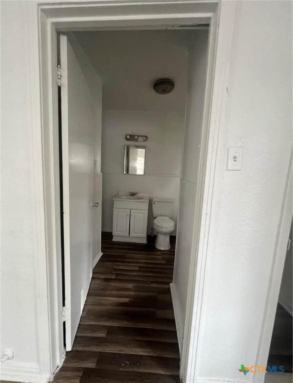 half bathroom featuring vanity, wood finished floors, and toilet