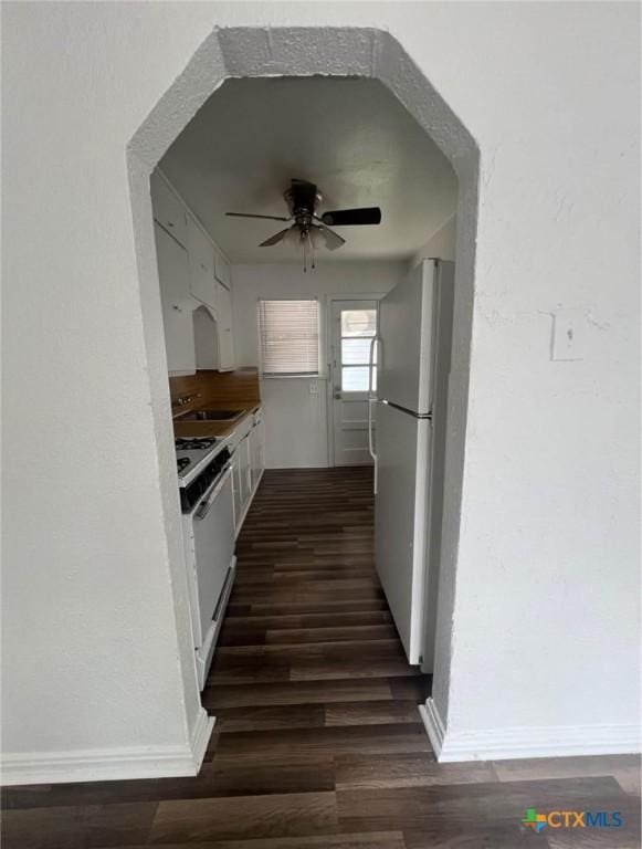 kitchen featuring dark wood-type flooring, a sink, ceiling fan, and white appliances