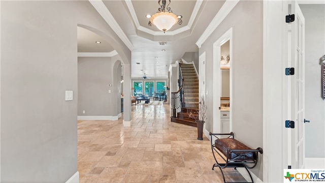 entryway with a tray ceiling and crown molding