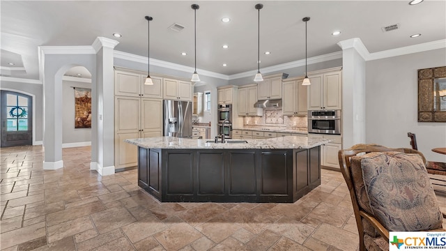 kitchen with appliances with stainless steel finishes, tasteful backsplash, decorative light fixtures, and an island with sink