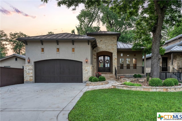 view of front of home with a garage, a lawn, and french doors