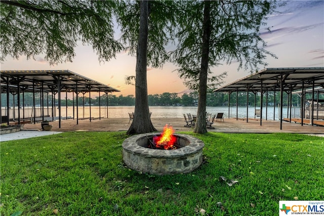 exterior space with a water view, an outdoor fire pit, and a lawn