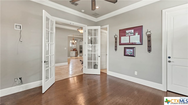 empty room featuring dark hardwood / wood-style flooring, ceiling fan with notable chandelier, french doors, and ornamental molding