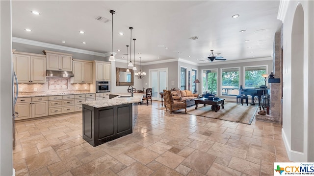 kitchen featuring cream cabinets, light stone counters, hanging light fixtures, oven, and backsplash