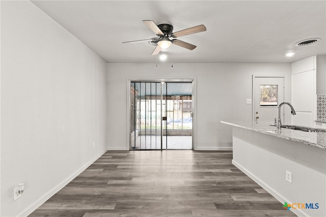 unfurnished dining area with ceiling fan, sink, and dark wood-type flooring