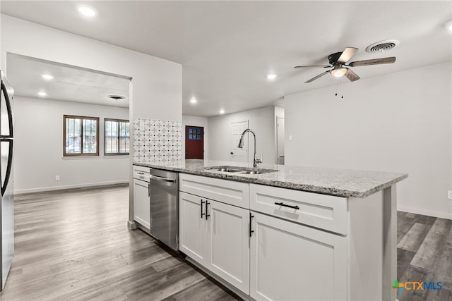 kitchen featuring light stone counters, stainless steel dishwasher, sink, white cabinets, and hardwood / wood-style floors