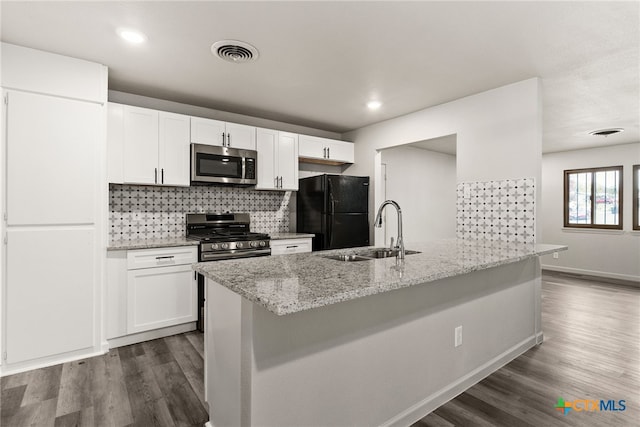 kitchen with sink, hardwood / wood-style flooring, light stone countertops, appliances with stainless steel finishes, and white cabinetry