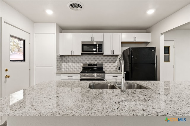 kitchen with sink, light stone countertops, appliances with stainless steel finishes, tasteful backsplash, and white cabinetry